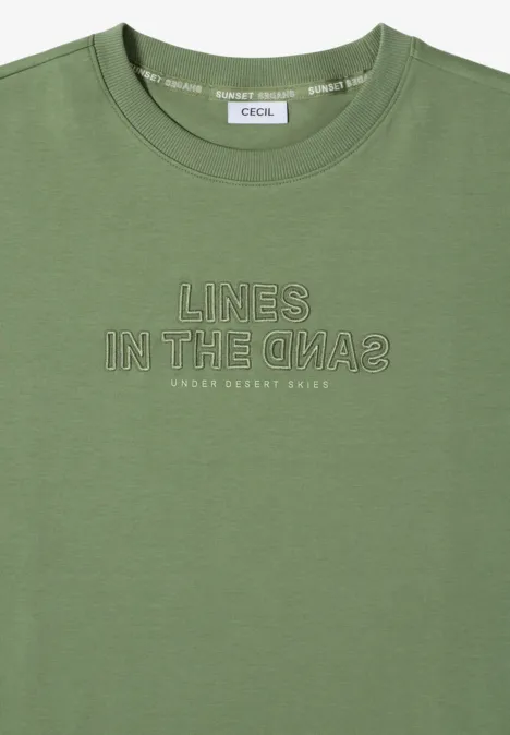 Bluza z krótkim rękawem i haftem deep matcha green Oliwkowy t-shirt z krótkim rękawem, białym nadrukiem 'LINES IN THE SAND2' i małym napisem 'UNDER DESERT SKIES'.