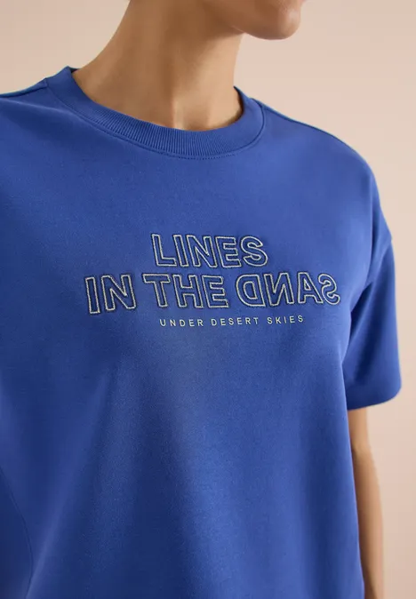 Bluza z krótkim rękawem z haftem deep river blue Niebieski t-shirt z napisem 'LINES IN THE OPA?' i małym tekstem 'UNDER DESSERT SKIES'.