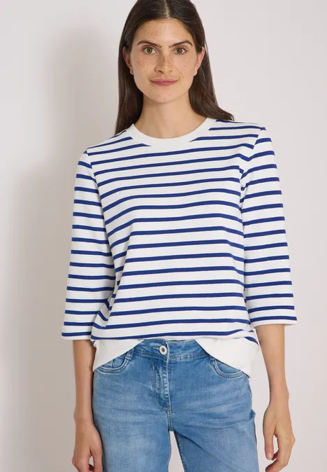 3/4-Arm Sweatshirt mit Rundhals und Streifen deep river blue Frau trägt weißes Shirt mit blauen Querstreifen und Dreiviertelärmeln, dazu blaue Jeans.