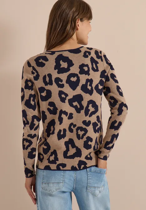 Vrouw van achteren in een beige trui met luipaardprint en blauwe spijkerbroek