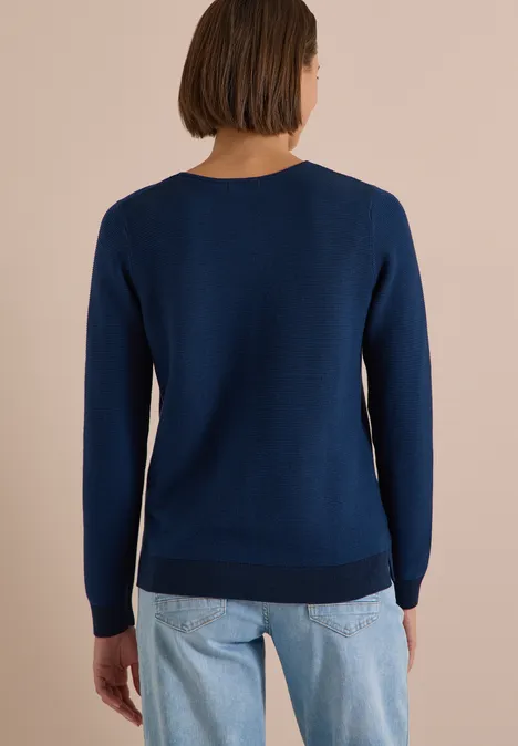 Person von hinten, trägt blauen Pullover und Jeans