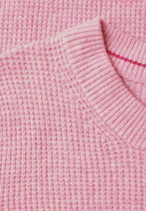 Close-up van een roze gebreide trui met ronde hals.