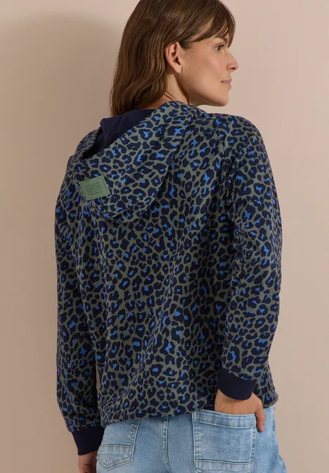 Sweatshirt mit Kapuze und Leo-Muster dried olive green Frau von hinten in blauem Leo-Kapuzenpullover und Jeans, neutraler Hintergrund.