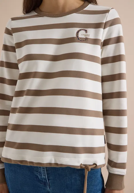 Weiß-beige gestreiftes Langarmshirt mit Rundhals und Kordelzug am Saum, dazu blaue Jeans.