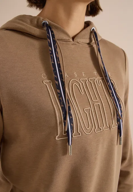 Beiger Kapuzenpullover mit großem 'LIGHT'-Schriftzug und blau-weißen gemusterten Kordeln.