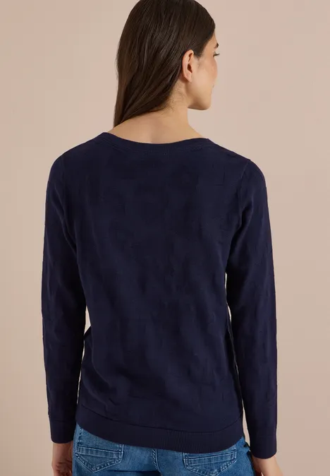 Pull à col bateau et texturé urban dark blue Rückansicht einer Frau in dunklem, langärmligem Pullover vor neutralem Hintergrund.