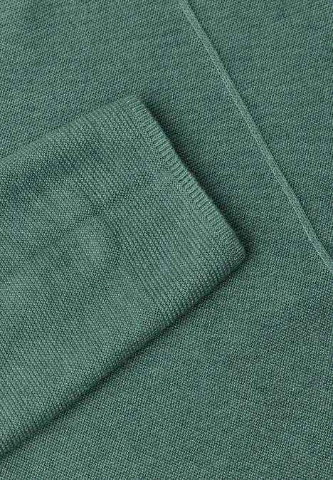Ein grüner Strickpullover mit gerippten Bündchen.