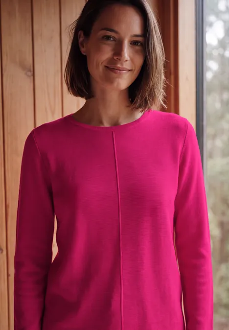 Langarm Pullover mit Rundhals und Struktur pink flash Eine lächelnde Frau in einem pinken Pullover steht in einem Raum mit Holzwänden.