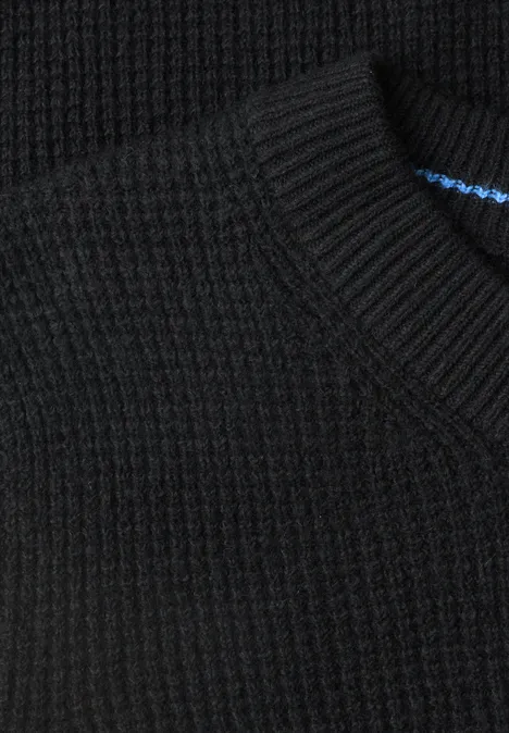 Gros plan d'un pull en maille noire côtelée avec encolure ronde.