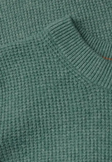 Nahaufnahme eines grünen Pullovers aus grobem Rippstrick mit Rundhalsausschnitt.
