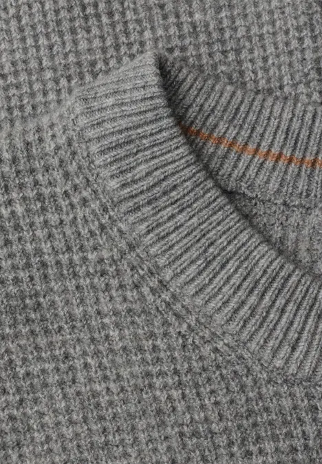 Nahaufnahme eines grauen Strickpullovers mit Waffelmuster und geripptem Kragen.