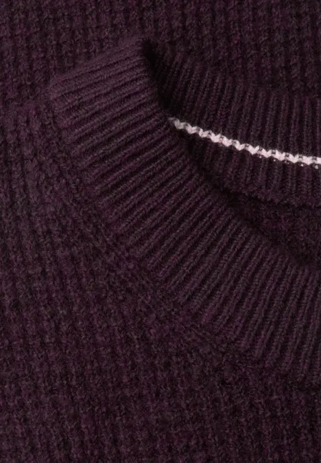 Nahaufnahme eines dunkelvioletten Rippstrick-Pullovers mit feinem weißen Nahtdetail im Kragen.