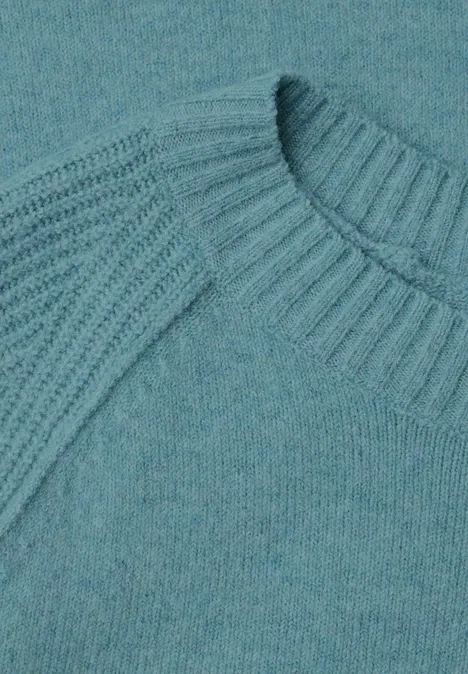 Detailaufnahme eines türkisfarbenen Strickpullovers mit Rippenmuster an Kragen und Schultern.