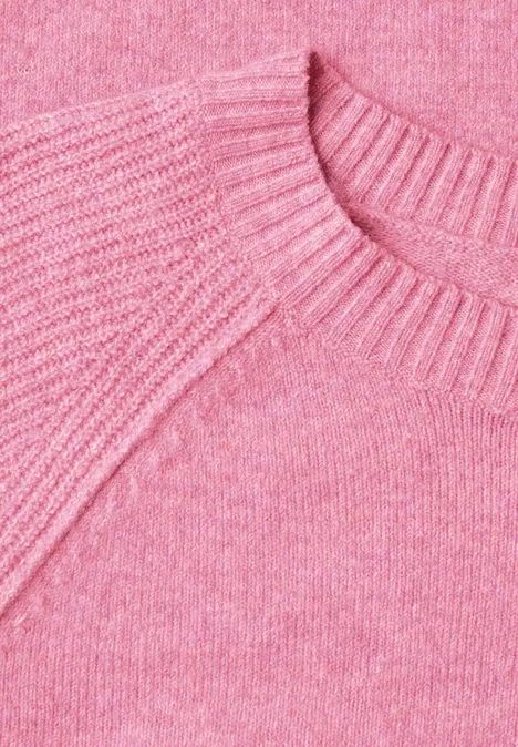 Close-up van een roze gebreide trui met ronde hals en fijne textuur.
