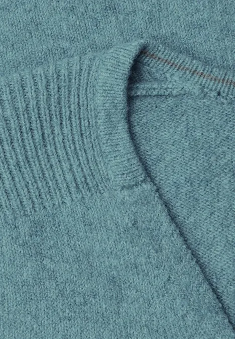 Close-up van een turquoise trui van fijn breiwerk met omgeslagen boord