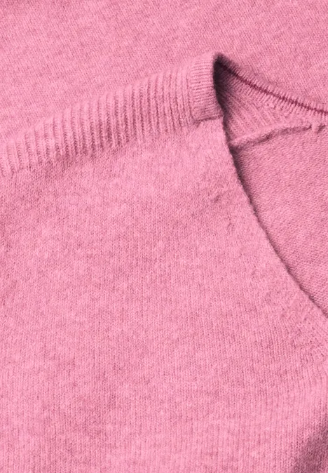 Close-up van een roze gebreide trui met ronde hals en fijne structuur.
