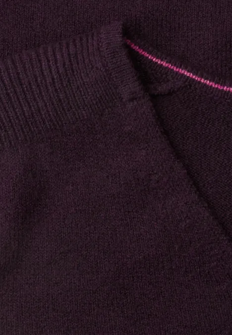 Nahaufnahme eines dunkelvioletten Strickstoffs mit Tasche und rosafarbenem Zierstich.