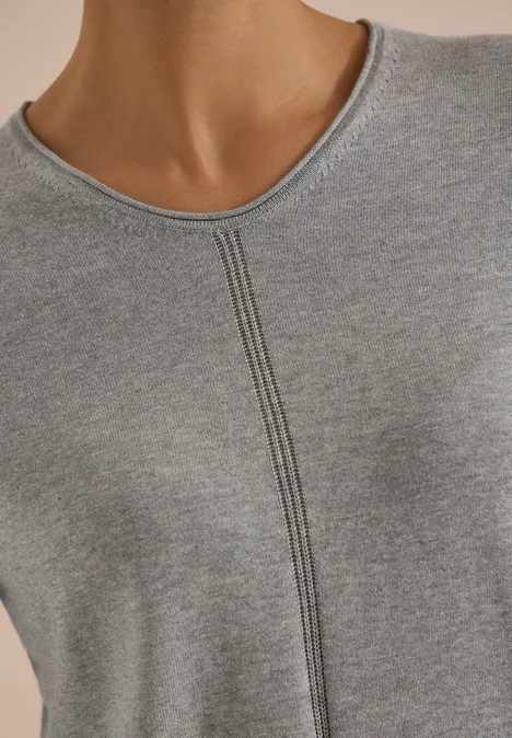 Nahaufnahme des Oberkörpers einer Person in grauem, fein geripptem Shirt mit zentraler Naht.