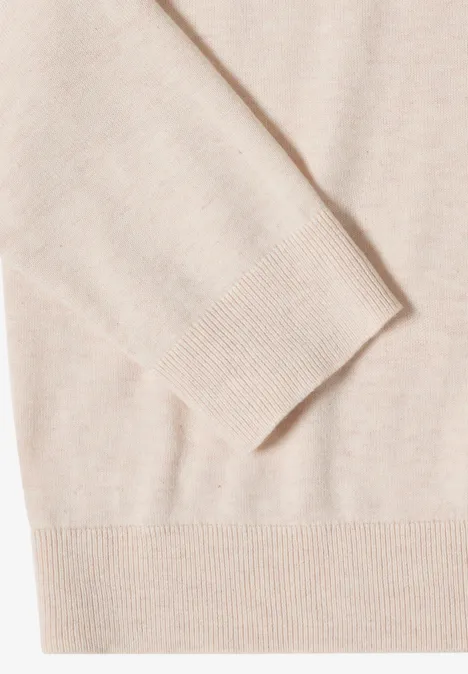 Nahaufnahme eines hellbeigen Strickpullovers mit Bündchen und feiner Struktur
