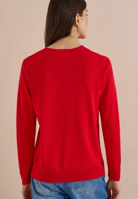 Frau in rotem Pullover und Jeans, gesehen von hinten.