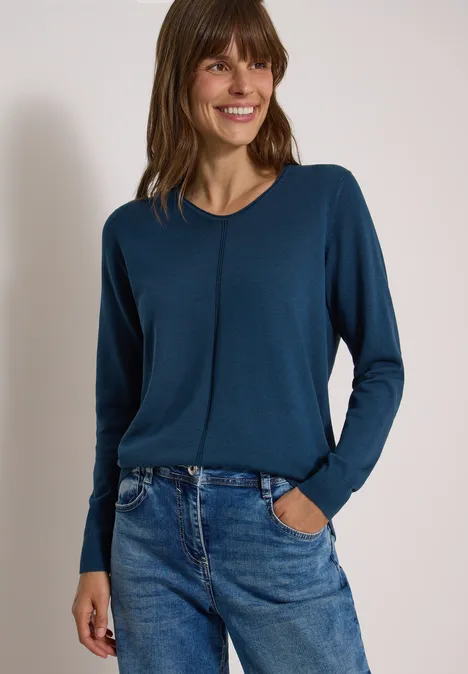 Basic Pullover mit V-Neck in Unifarbe moonlight blue Eine lächelnde Frau trägt ein petrolfarbenes Langarmshirt und blaue Jeans, steht vor weißem Hintergrund.