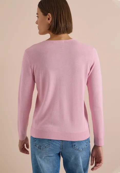 Frau mit kurzem Bob trägt rosa Pullover und blaue Jeans, Rückansicht.