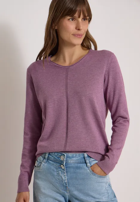 Basic Pullover mit V-Neck in Unifarbe lavender purple melange Junge Frau im violetten Pullover mit vertikalem Ziernaht und Jeans, Hände in Hosentaschen.