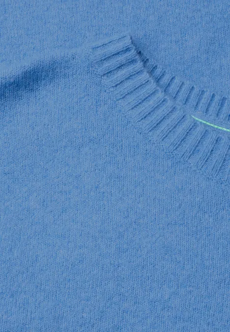 Close-up van een lichtblauwe trui met zachte, pluizige stof bij de hals.