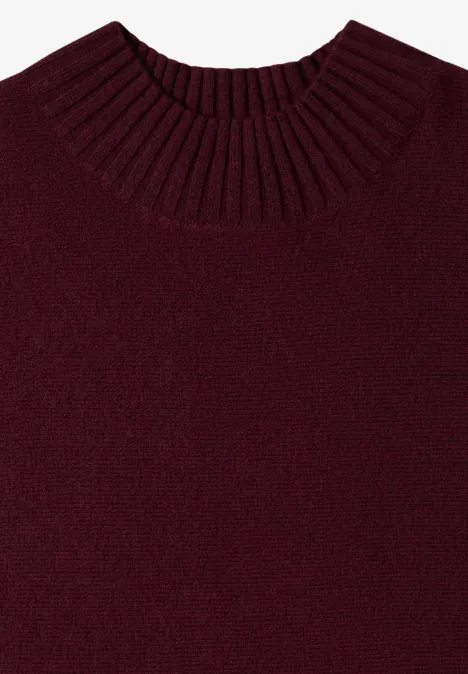 Ein schlichtes, dunkelrotes Strickshirt mit geripptem Rundhalsausschnitt, flach liegend fotografiert.