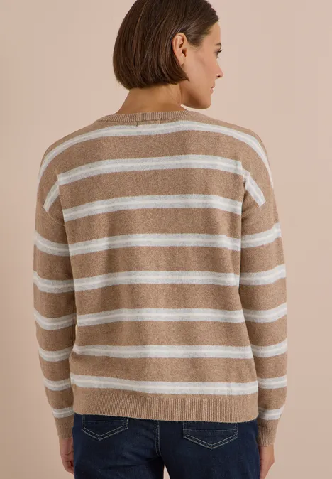 Femme vue de dos portant un pull beige à rayures blanches.