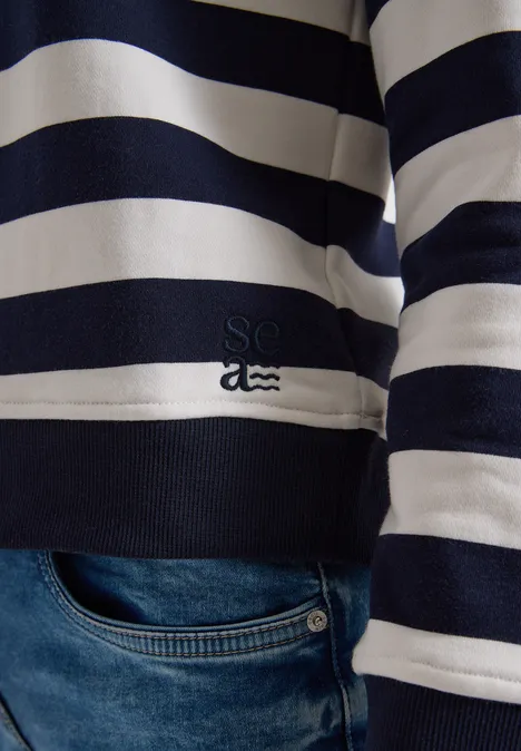Nahaufnahme eines dunkelblau-weiß gestreiften Pullovers über Jeans.