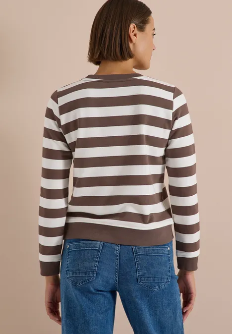 Frau von hinten in gestreiftem Braun-Weiß-Pullover und blauen Jeans, kurzhaarig.
