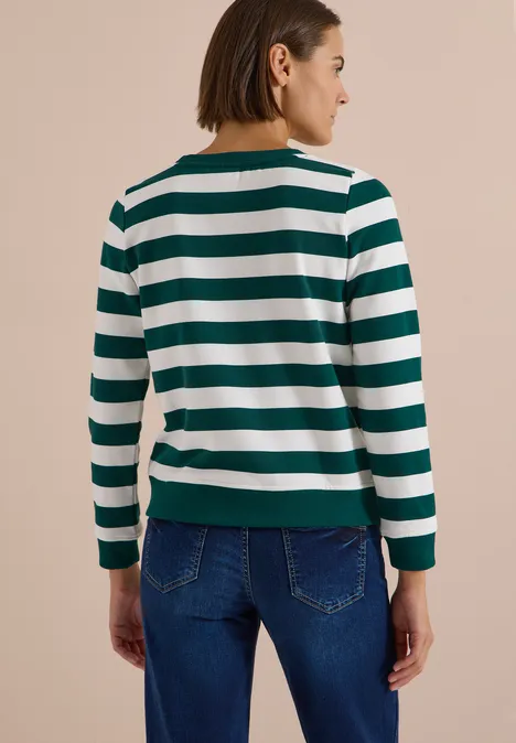 Rückansicht einer Person in grün-weiß gestreiftem Langarmshirt und blauen Jeans.