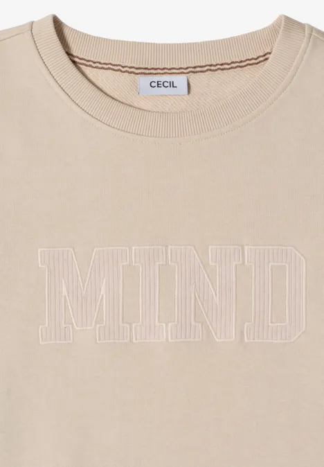 T-shirt beige avec inscription 'MIND' en contours blancs et étiquette 'CECIL' à l'intérieur