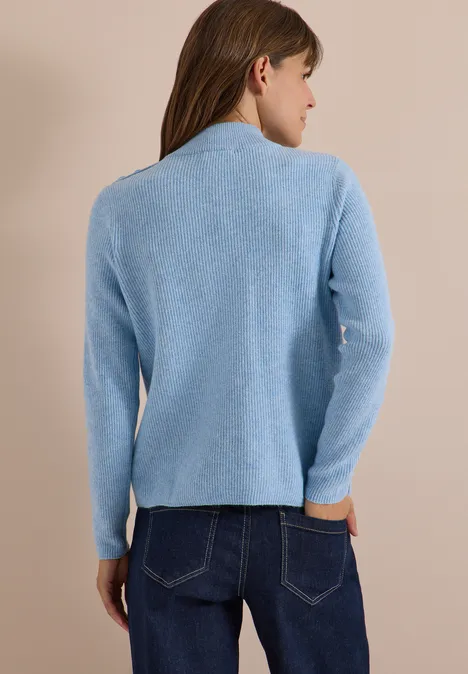 Pull texturé avec des boutons décoratifs easy blue melange Femme vue de dos portant un pull bleu clair et un jean, fond beige.