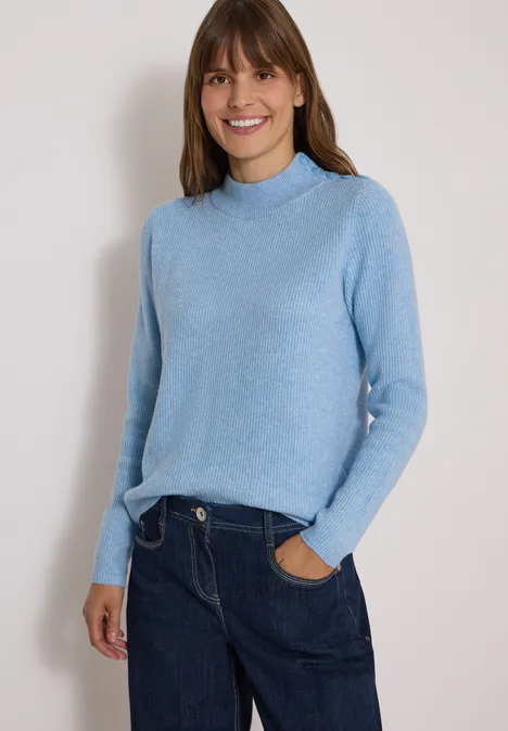 Pull texturé avec des boutons décoratifs easy blue melange Femme souriante portant un pull bleu clair et un jean foncé sur fond neutre.