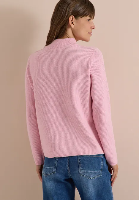 Pull texturé avec boutons décoratifs mellow rose melange Femme de dos portant un pull rose et un jean bleu sur fond neutre.