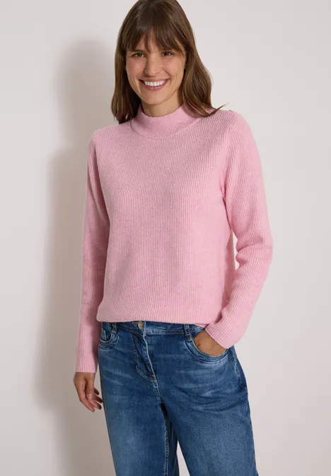 Pull texturé avec boutons décoratifs mellow rose melange Femme souriante portant un pull rose et un jean bleu sur fond clair.