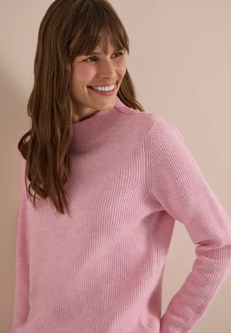 Pull texturé avec boutons décoratifs mellow rose melange Une femme souriante aux cheveux bruns mi-longs porte un pull rose.