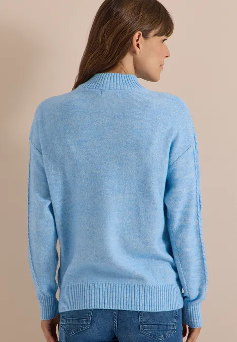 Femme de dos en pull bleu clair et jean.