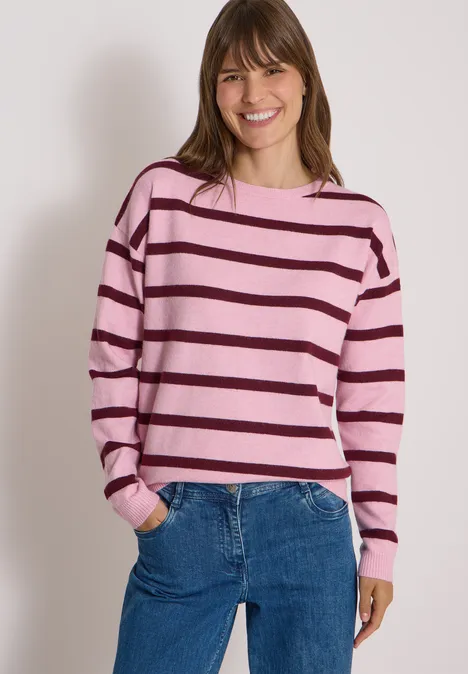 Pull à col bateau et rayures mellow rose melange Femme souriante en pull rayé rose et jean bleu.