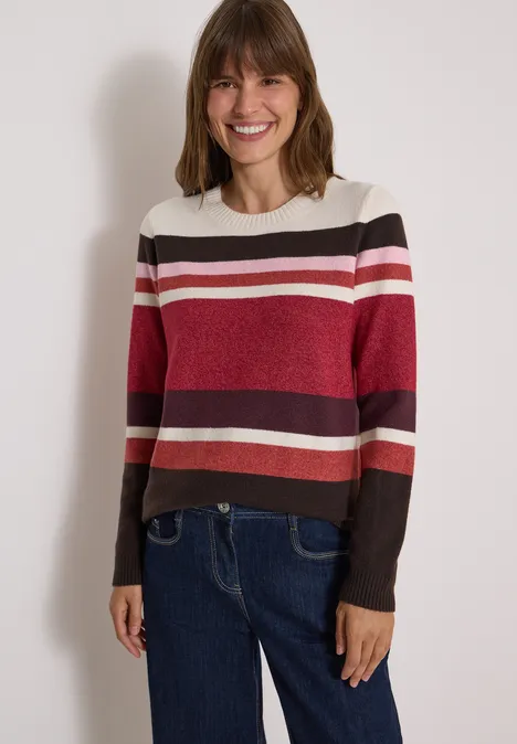 Pull à col rond et rayures rhubarb melange Femme souriante portant un pull à rayures et un jean.