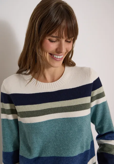 Pull à col rond et à rayures mineral blue melange Femme souriante portant un pull rayé bleu, vert et écru devant un fond clair.