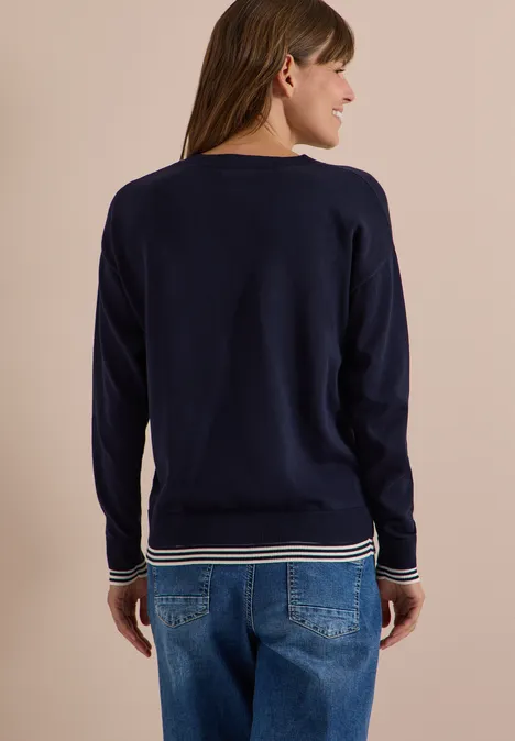 Pull à col rond avec détail superposé urban dark blue Femme de dos portant un pull bleu marine avec rayures blanches aux bords et un jean bleu.
