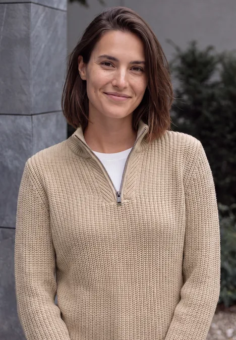 Pullover in Unifarbe mit Zipper creamy mocha melange Eine lächelnde Frau in beigem Pullover und weißem T-Shirt vor neutralem Hintergrund.