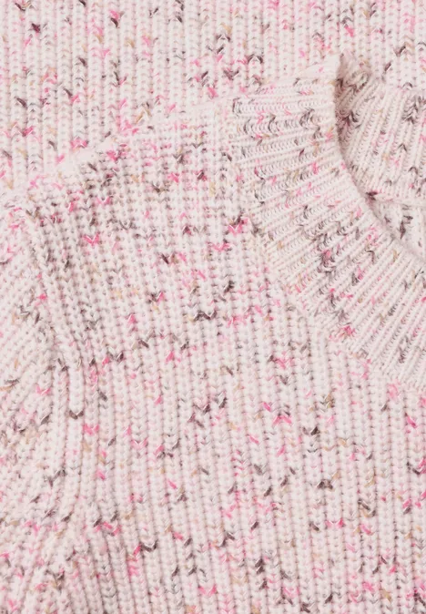 Nahaufnahme eines cremefarbenen, gerippten Strickpullovers mit zartrosa Sprenkeln.