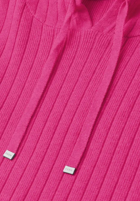 Close-up van een felroze gebreide hoodie met capuchon en koordjes met metalen uiteinden.