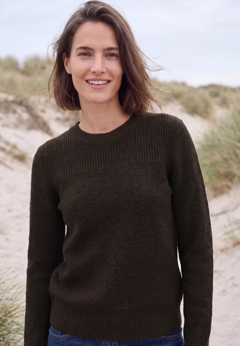 Glimlachende vrouw in donkere trui voor duinenlandschap