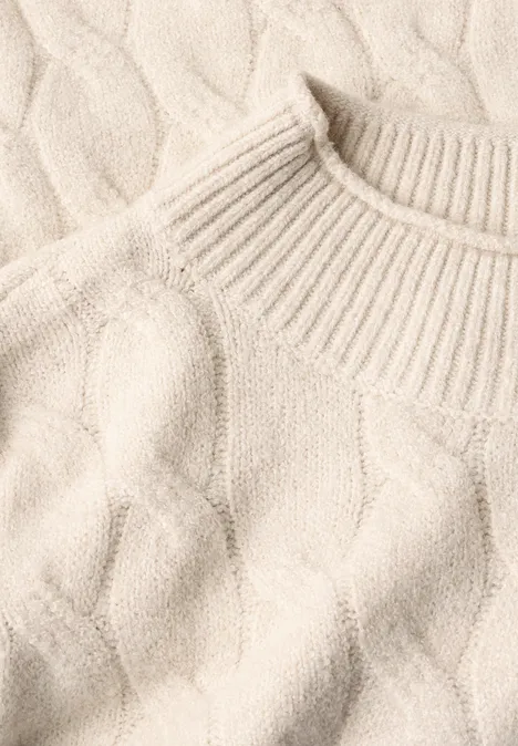 Pullover mit Turtle Neck und Zopfmuster oat milk beige melange Detailaufnahme eines cremefarbenen Strickpullovers mit Zopfmuster und hohem Kragen.