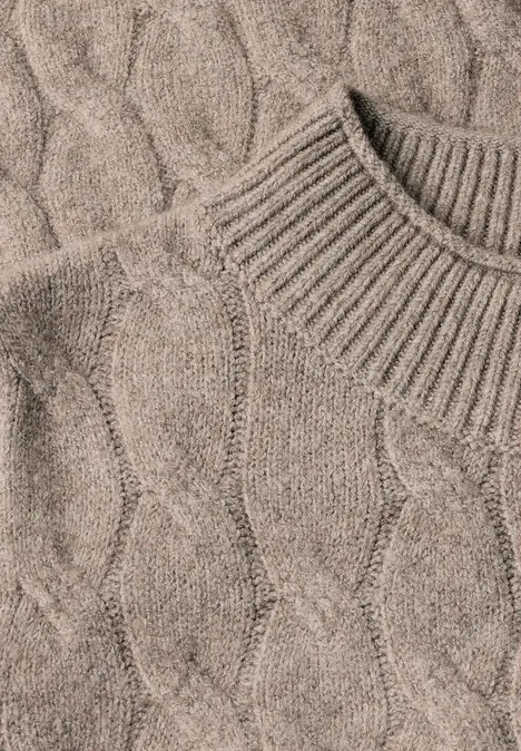 Beiger, grob gestrickter Pullover mit Zopfmuster und hohem Kragen.